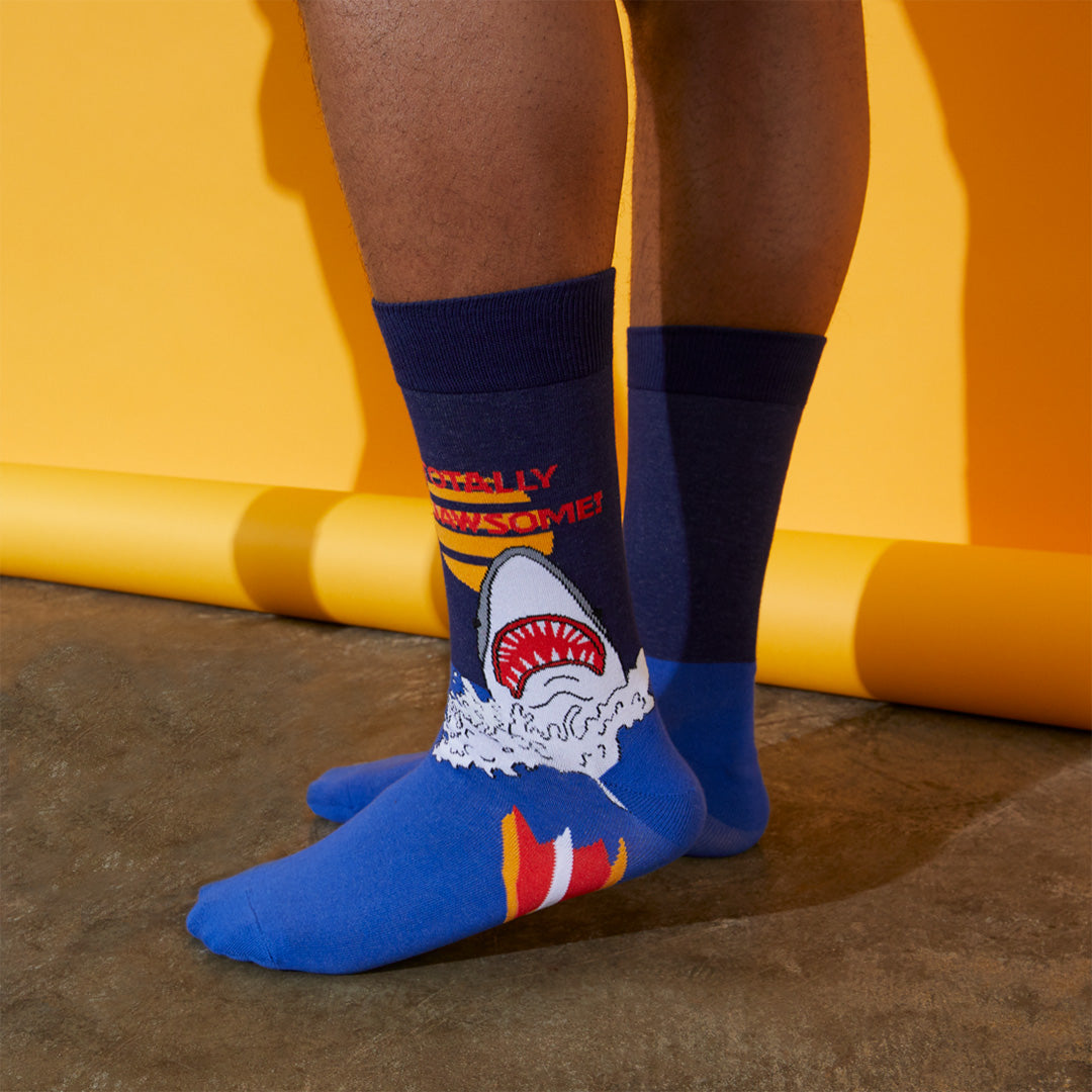Person wearing blue socks with shark design against a yellow background